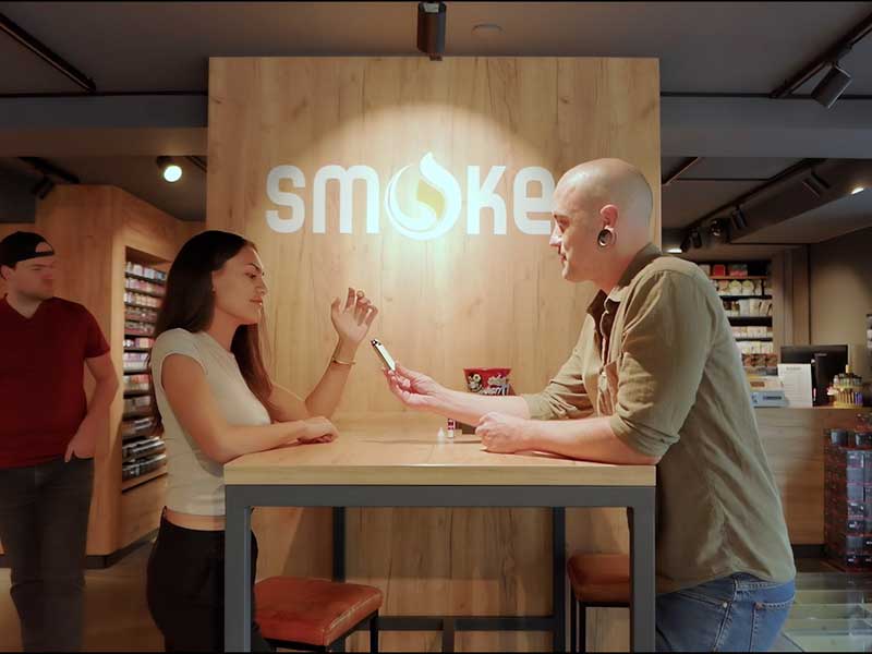 Beratungssituation im Smokee Store, bei der ein Mitarbeiter einer Kundin ein Vape-Produkt erklärt und das Einkaufserlebnis persönlich gestaltet.