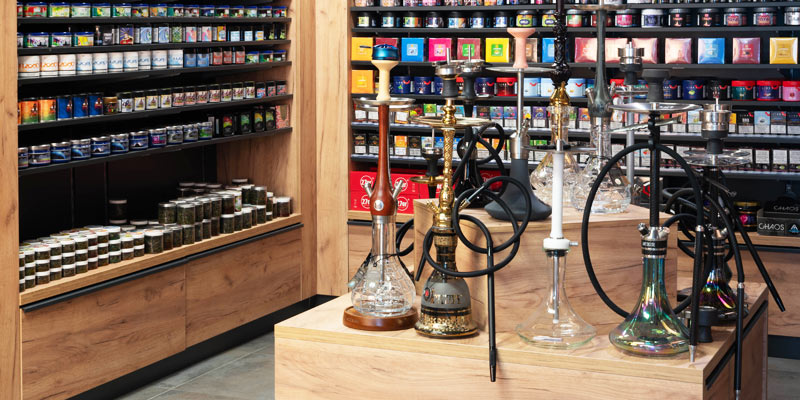 Innenansicht der Smokee Filiale Baden mit umfangreicher Shisha- und Tabakauswahl sowie modernen Holzregalen.