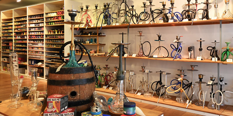 Innenaufnahme der Smokee Filiale Olten mit zahlreichen Shishas, Tabaksorten und Zubeh&ouml;r auf Wandregalen und Tischen.