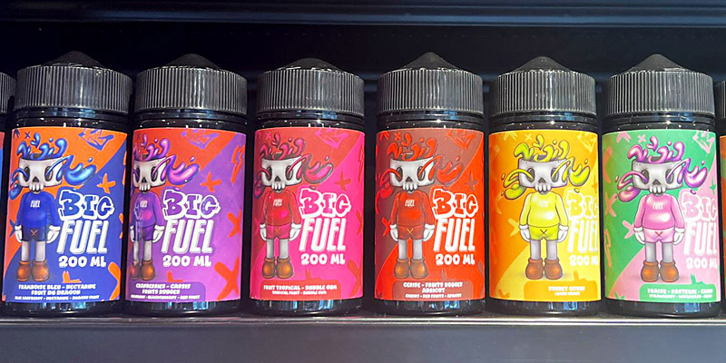 Sechs bunte Big Fuel E-Liquid Flaschen à 200ml in verschiedenen Geschmacksrichtungen von Blaubeere bis Tropical, aufgereiht im Regal