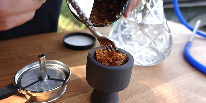 Shisha-Kopf, der von einer Shisha-Gabel mit Shisha-Tabak befüllt wird.