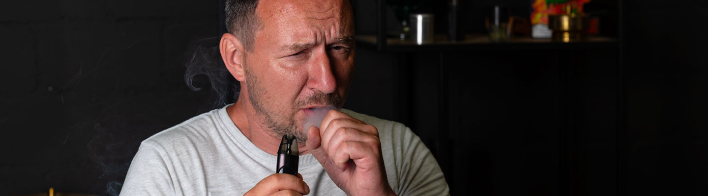 Mann mit E-Zigarette beim Dampfen mit unangenehmem Gesichtsausdruck – möglicher Dry Hit