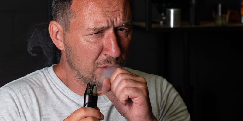 Mann mit E-Zigarette beim Dampfen mit unangenehmem Gesichtsausdruck – möglicher Dry Hit