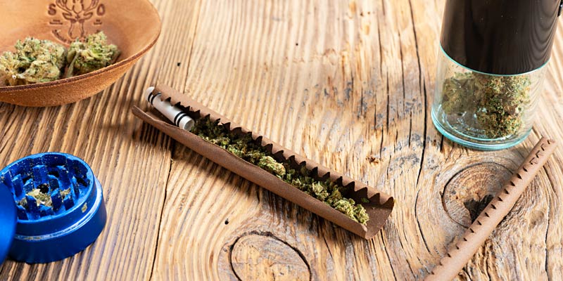 Cannabis-Produkte auf einem Metalltisch mit Holzschale und Plastikbehälter.