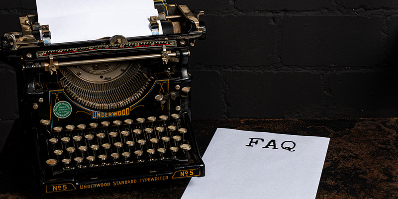 Vintage-Schreibmaschine der Marke Underwood neben einem Papier mit dem Aufdruck &laquo;FAQ&raquo; &ndash; Symbolbild f&uuml;r h&auml;ufig gestellte Fragen.