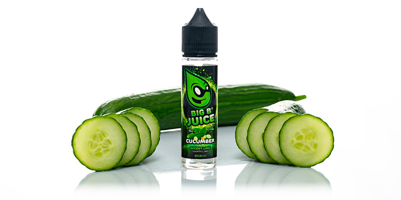 Ein stehendes Big B Juice Shorfill Liquid mit Gurken-Geschmack, umgeben von einer frischen Gurke mit Ringen