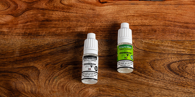 Zwei Fläschchen Crossbow-Nikotinsalze auf einer Holzoberfläche