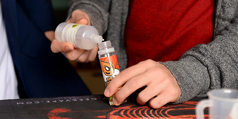 Person f&uuml;llt eine E-Liquid Flasche nach