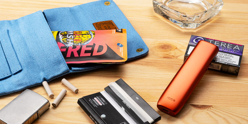 Tabakerhitzer, Zigarettenetui und Drehtabak-Utensilien auf Holztisch – Tabakgenuss ohne Rauch bei Smokee.ch