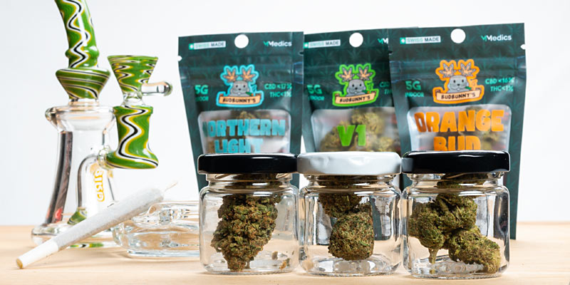 Häufig gestellte Fragen zu Budbunny's: Bild mit drei Packungen CBD-Blüten von Budbunny und Blüten in Gläsern 