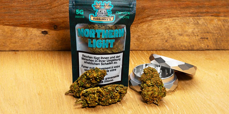 Eine Packung CBD-Blüten Budbunny's Northern Light mit Blüten und Grinder 