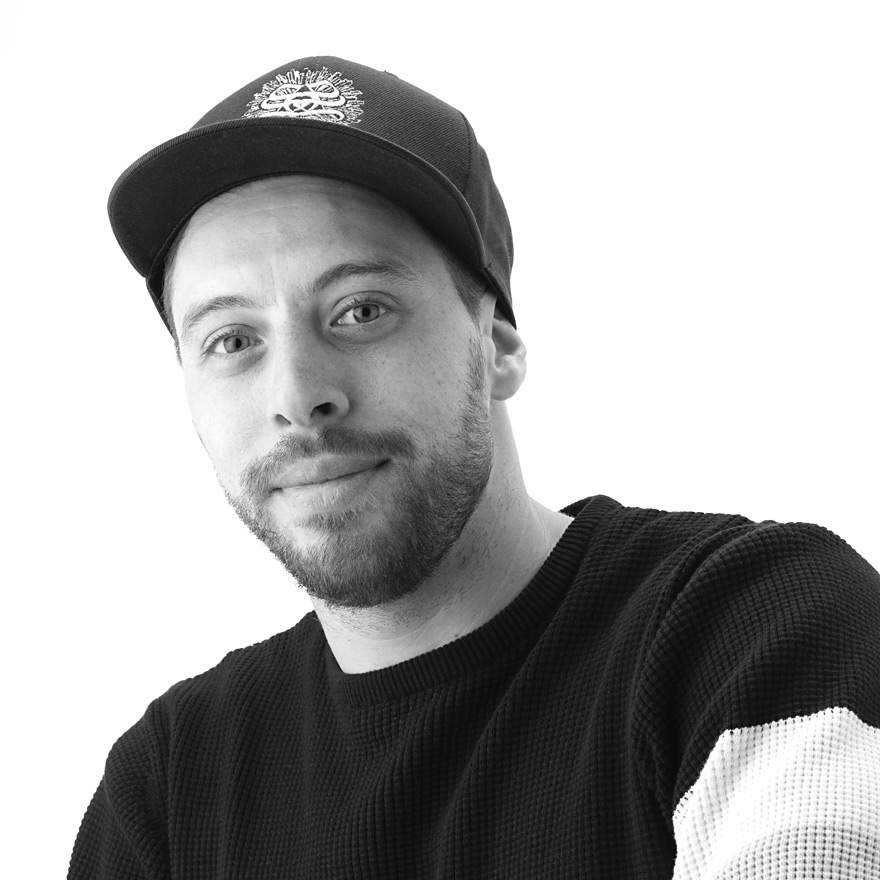 Porträt von Yanis, Mitarbeiter bei Smokee Baden, mit Cap und Pullover, vor hellem Hintergrund.