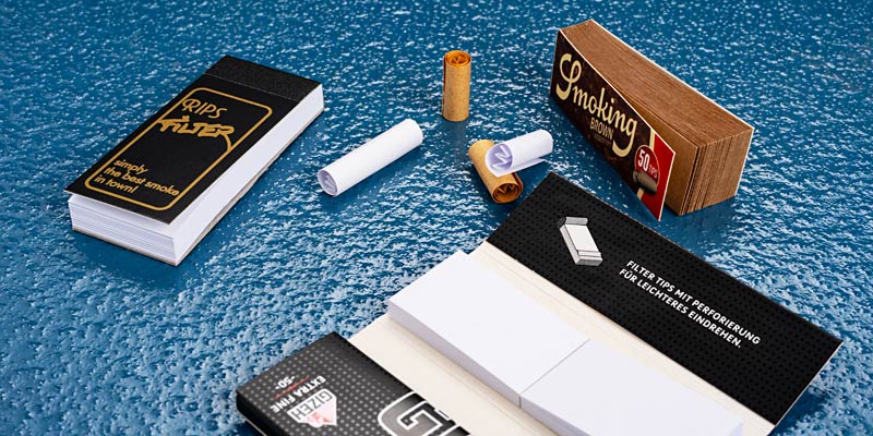 Verschiedene Papierfilter und Filtertips von Smoking, Gizeh, Rips und weiteren Marken auf Holzoberfläche