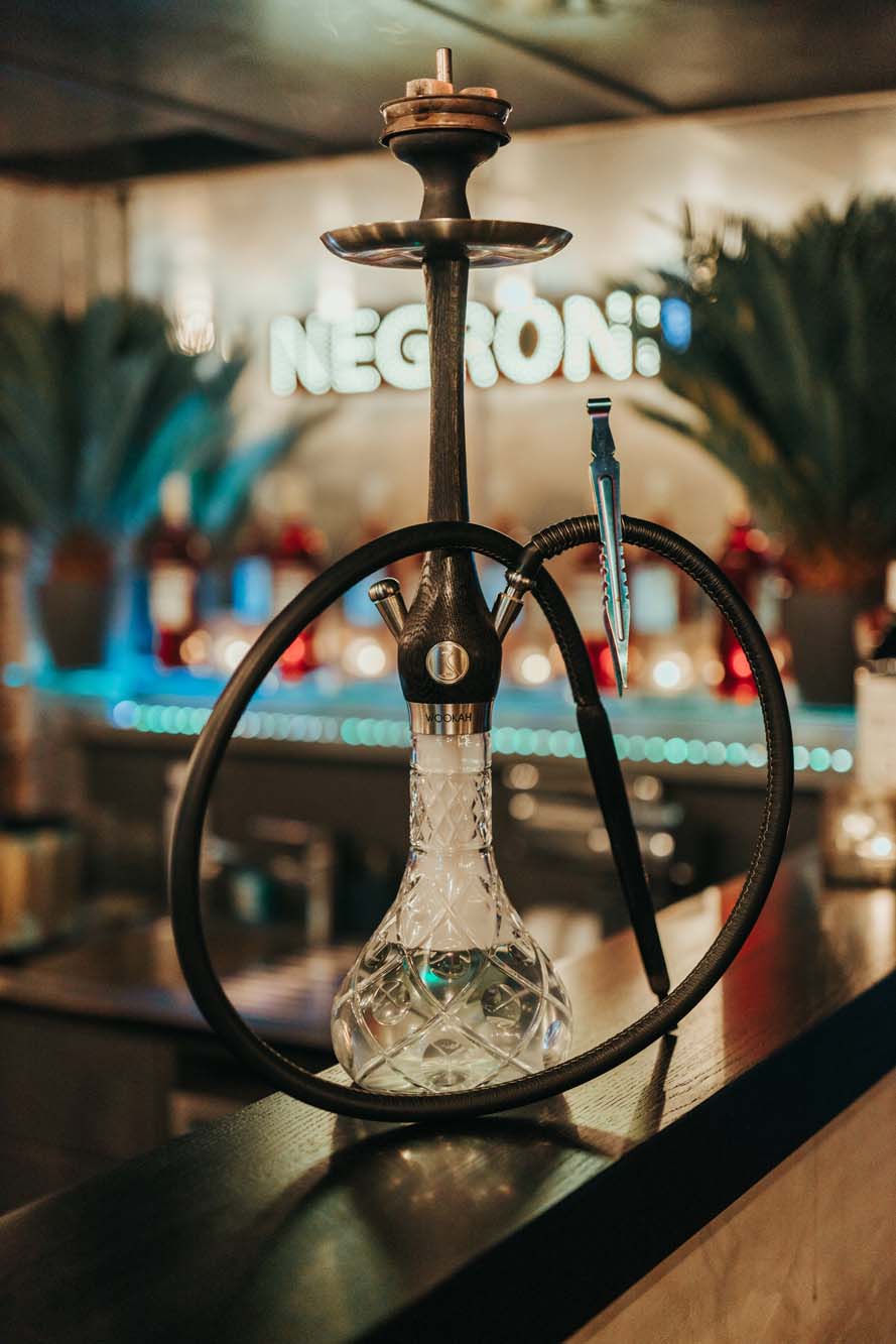 Hochwertige Shisha mit Kristallglas-Bowl und schwarzem Schlauch auf Bartresen in stilvoller Lounge.