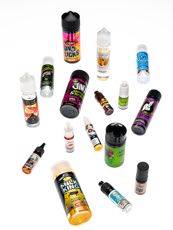 Auswahl verschiedener Vape-Liquids in bunten Flaschen, flach auf weissem Hintergrund fotografiert.