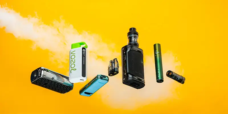 Eine Nahaufnahme von verschiedenen Vaping-Ger&auml;ten und Zubeh&ouml;rteilen auf einem gelben Hintergrund